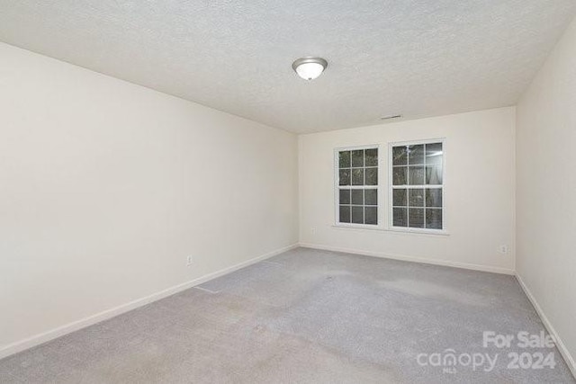 unfurnished room with a textured ceiling and light colored carpet