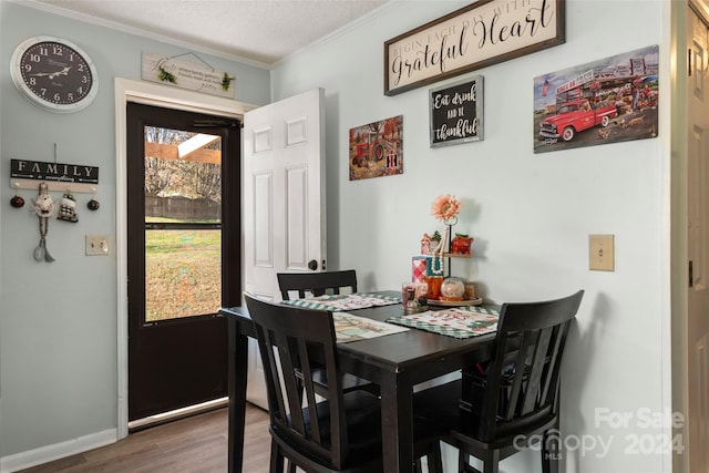 dining area with dark hardwood / wood-style flooring, ornamental molding, and a textured ceiling