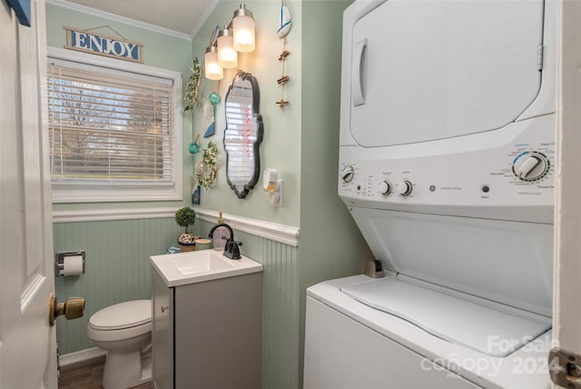 bathroom with vanity, crown molding, hardwood / wood-style flooring, toilet, and stacked washing maching and dryer