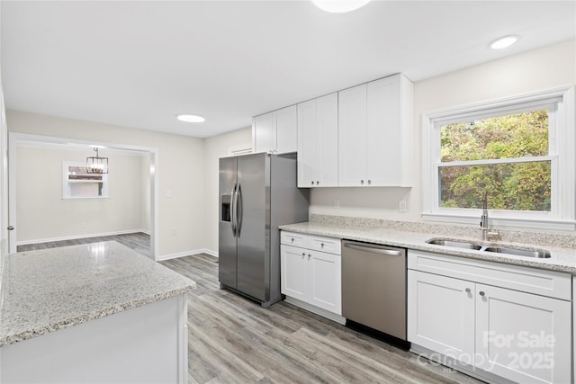 kitchen with white cabinetry, sink, light stone counters, and appliances with stainless steel finishes