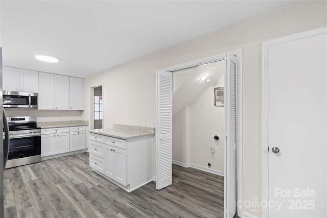 kitchen with light stone countertops, white cabinets, light hardwood / wood-style floors, and appliances with stainless steel finishes