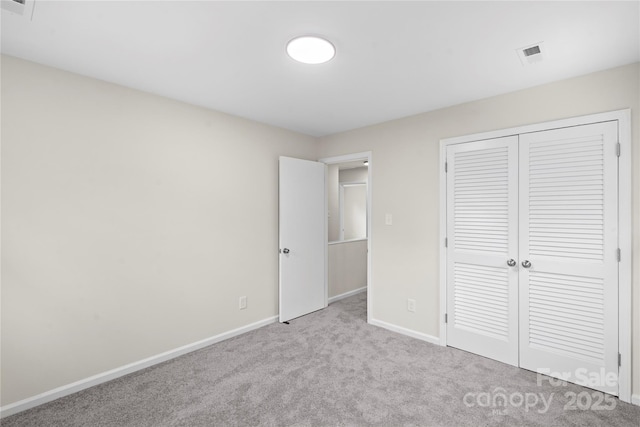 unfurnished bedroom with light carpet and a closet