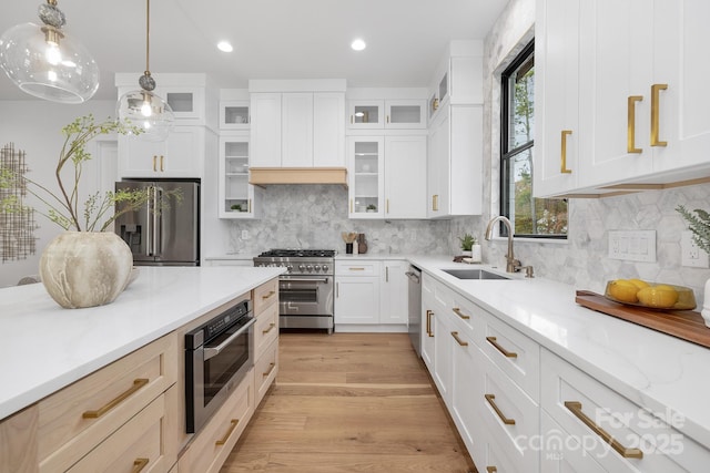 kitchen featuring light stone countertops, hanging light fixtures, decorative backsplash, white cabinets, and high end appliances