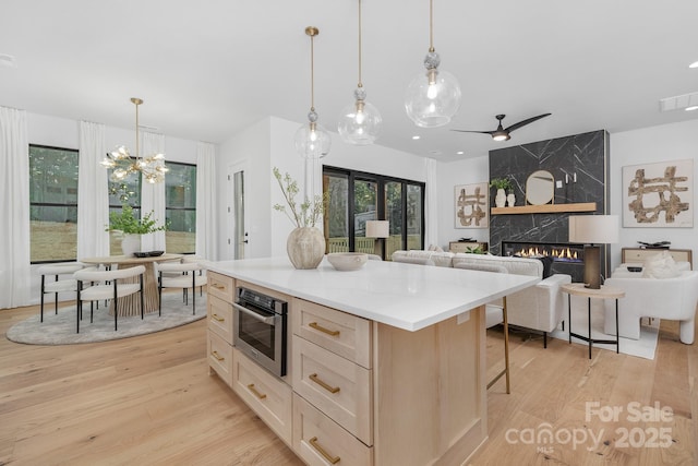 kitchen with a center island, light hardwood / wood-style flooring, decorative light fixtures, a kitchen bar, and a fireplace