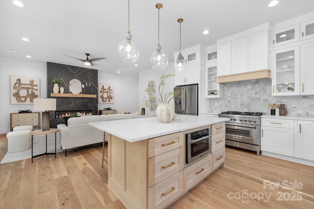 kitchen featuring tasteful backsplash, a high end fireplace, pendant lighting, high quality appliances, and a kitchen island