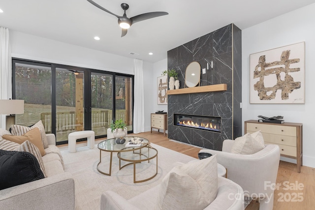 living room with ceiling fan, a fireplace, and light wood-type flooring