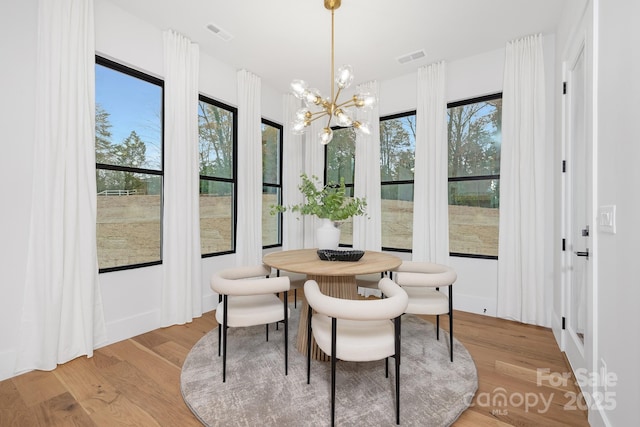 dining area with light wood-type flooring, an inviting chandelier, and a wealth of natural light