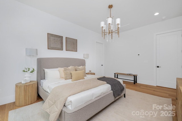 bedroom with light wood-type flooring and an inviting chandelier