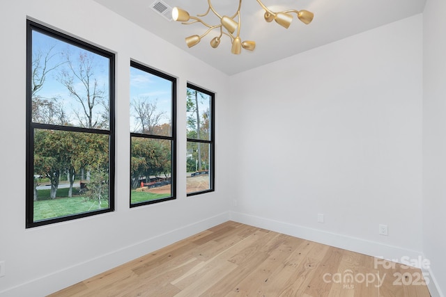 spare room with hardwood / wood-style flooring and an inviting chandelier