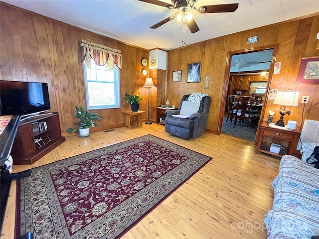 living room featuring hardwood / wood-style floors, wood walls, and ceiling fan