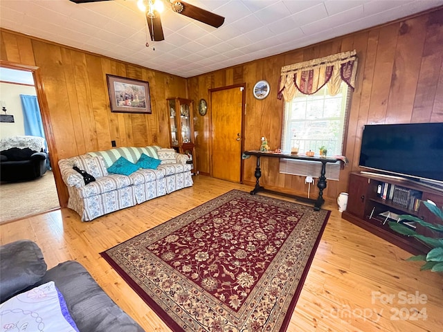 living room featuring wood walls, ceiling fan, and light hardwood / wood-style flooring