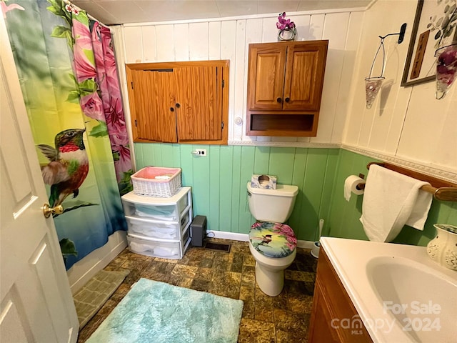 full bathroom featuring vanity, toilet, wooden walls, and shower / bathtub combination with curtain