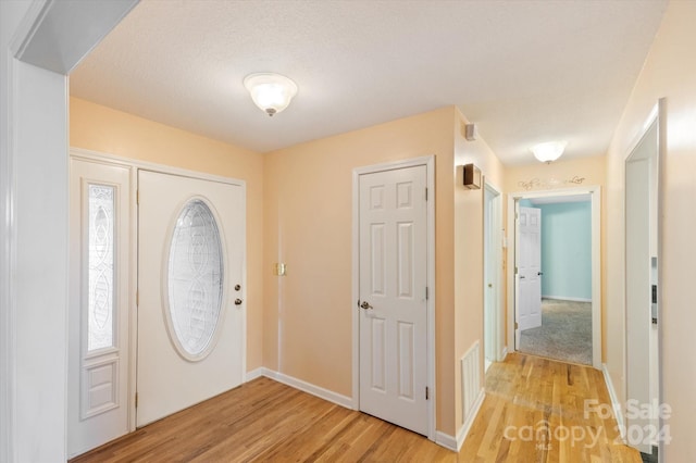 entrance foyer with light wood-type flooring and a textured ceiling