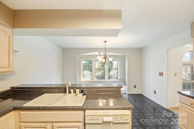 kitchen featuring white dishwasher, sink, light brown cabinets, and a notable chandelier