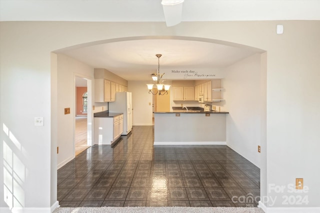 kitchen with white fridge, decorative light fixtures, kitchen peninsula, and a notable chandelier