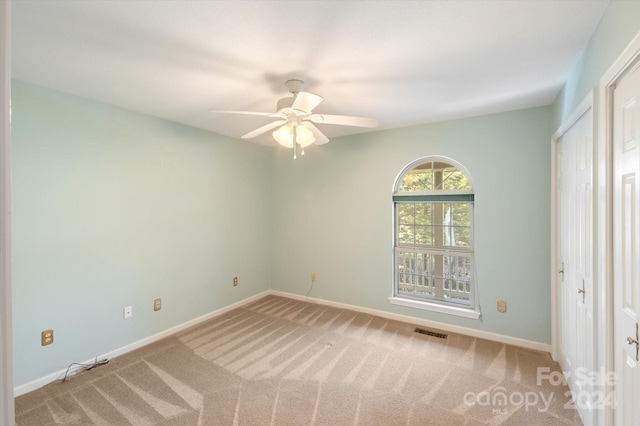 unfurnished room featuring light carpet and ceiling fan