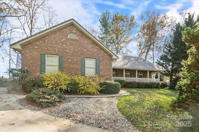 view of front of property featuring covered porch, a front yard, and brick siding