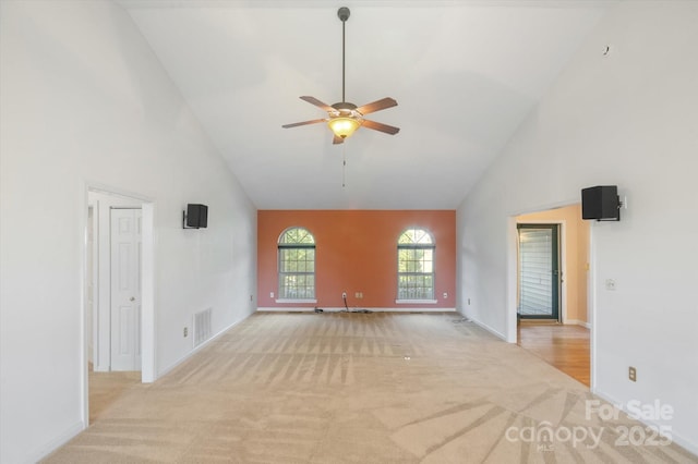 unfurnished living room with high vaulted ceiling, a ceiling fan, visible vents, and light colored carpet