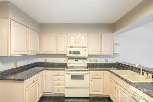 kitchen with white appliances, dark stone counters, and a sink