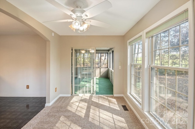 unfurnished room with ceiling fan, baseboards, visible vents, and arched walkways