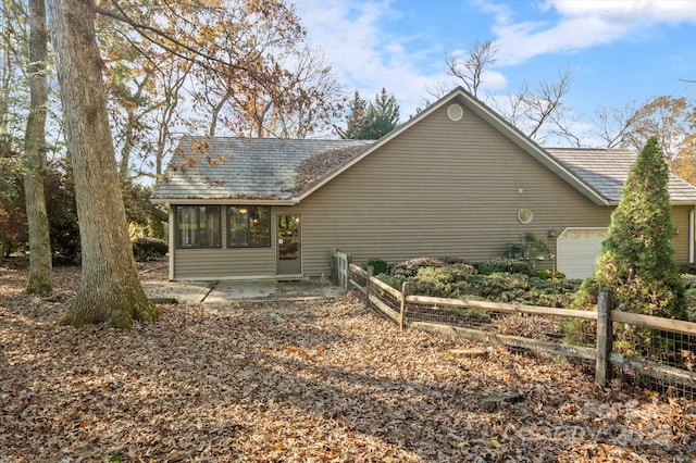 exterior space featuring a garage, a sunroom, and fence