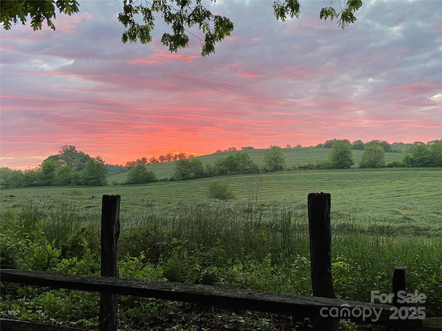 yard at dusk featuring a rural view