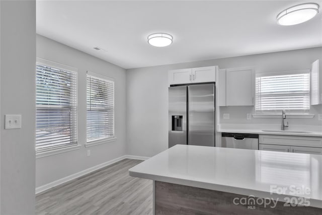 kitchen with white cabinetry, stainless steel appliances, sink, and a wealth of natural light