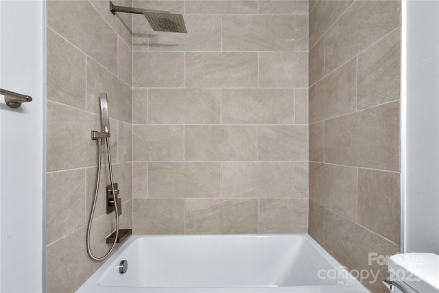 bathroom featuring tiled shower / bath and toilet