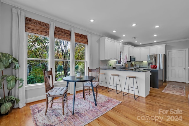 kitchen featuring appliances with stainless steel finishes, backsplash, light hardwood / wood-style flooring, and white cabinetry