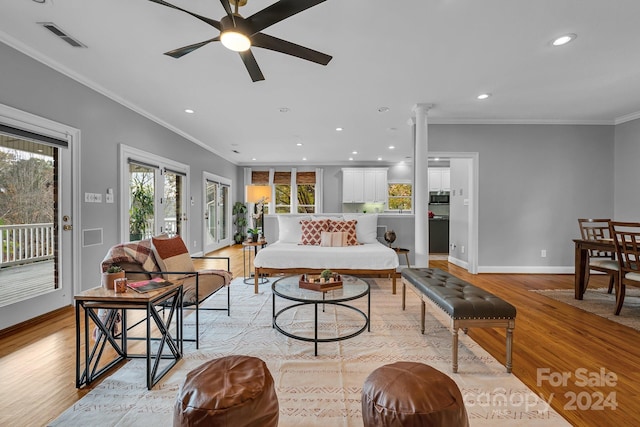 living room with light wood-type flooring, ornate columns, ceiling fan, and ornamental molding