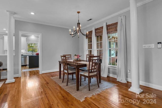 dining room with ornate columns, crown molding, a chandelier, and light wood-type flooring