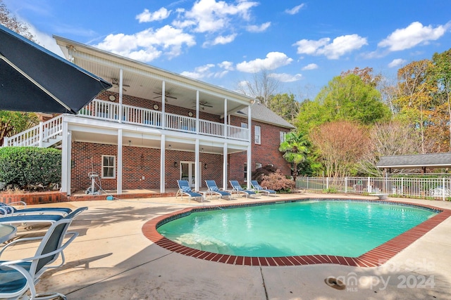 view of swimming pool featuring ceiling fan, a diving board, and a patio area