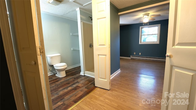 bathroom with a baseboard heating unit, ceiling fan, a textured ceiling, hardwood / wood-style flooring, and toilet