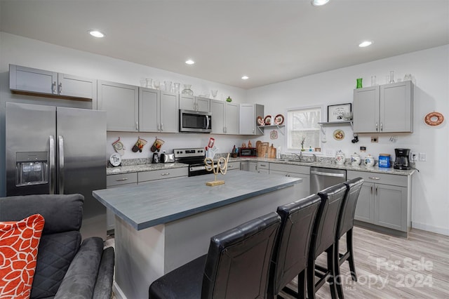 kitchen featuring a breakfast bar area, stainless steel appliances, sink, a center island, and light hardwood / wood-style floors