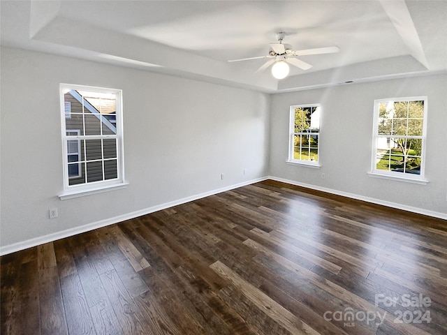 spare room with ceiling fan, a tray ceiling, and dark hardwood / wood-style flooring