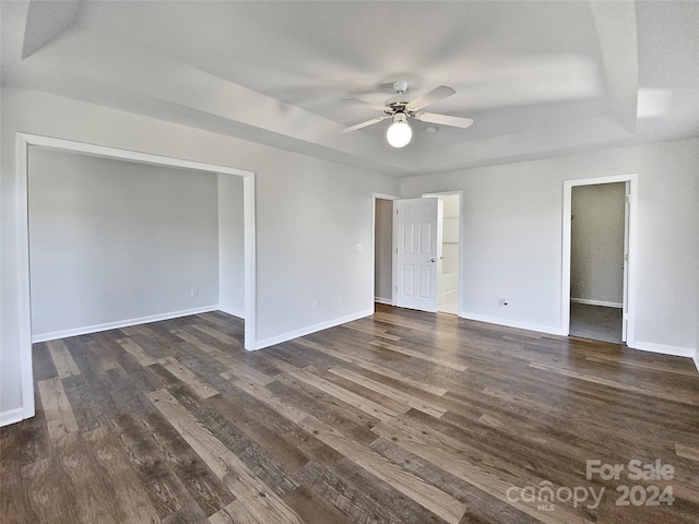 unfurnished room featuring dark wood-type flooring, a raised ceiling, and ceiling fan