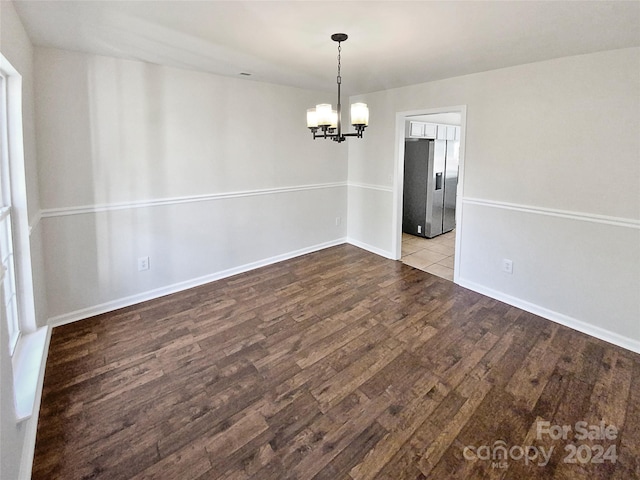 unfurnished dining area featuring a notable chandelier and hardwood / wood-style flooring