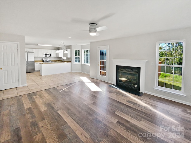 unfurnished living room featuring light hardwood / wood-style flooring, ceiling fan, and a wealth of natural light