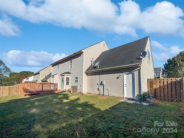 rear view of property with a deck, a lawn, and central AC unit