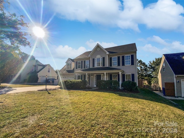 view of front of home with a front yard, covered porch, and a garage