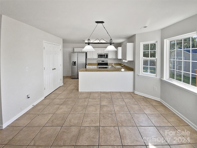 kitchen with kitchen peninsula, white cabinets, hanging light fixtures, sink, and stainless steel appliances