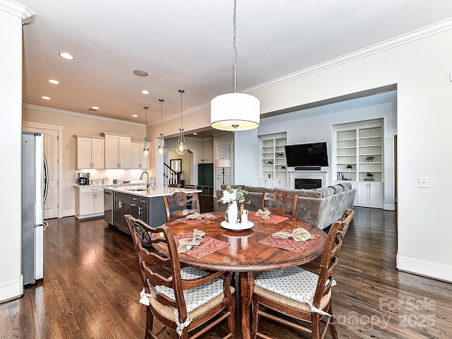 dining room featuring crown molding, built in features, dark wood-type flooring, and sink