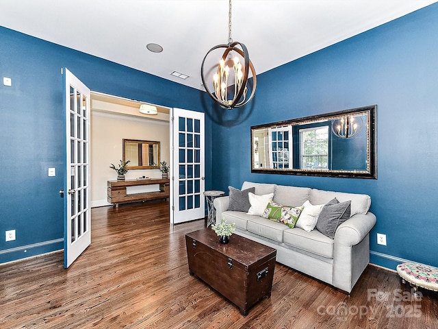 living room featuring dark hardwood / wood-style flooring, french doors, and an inviting chandelier