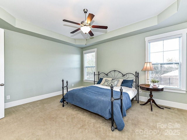 bedroom with a tray ceiling, ceiling fan, and light colored carpet