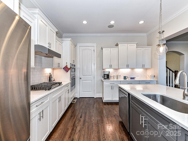 kitchen with backsplash, sink, hanging light fixtures, appliances with stainless steel finishes, and white cabinetry