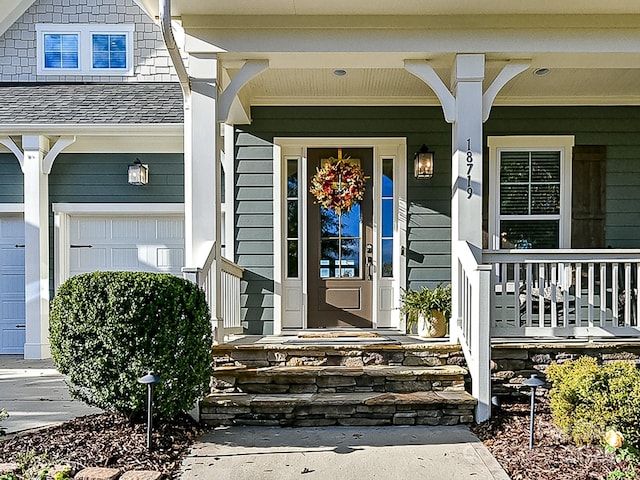 view of exterior entry with covered porch and a garage