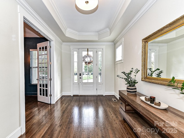 entryway with crown molding, dark wood-type flooring, and a tray ceiling