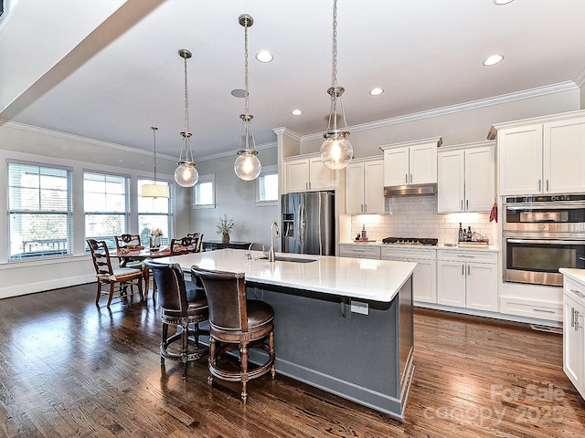 kitchen featuring a center island with sink, white cabinets, pendant lighting, and appliances with stainless steel finishes