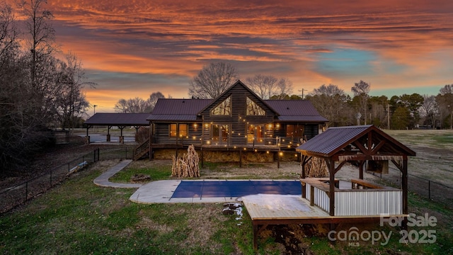 back house at dusk featuring a patio area and a swimming pool side deck