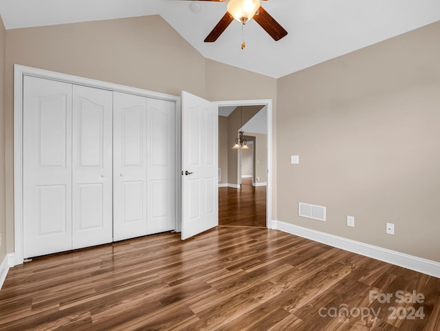 unfurnished bedroom featuring dark hardwood / wood-style flooring, lofted ceiling, ceiling fan, and a closet